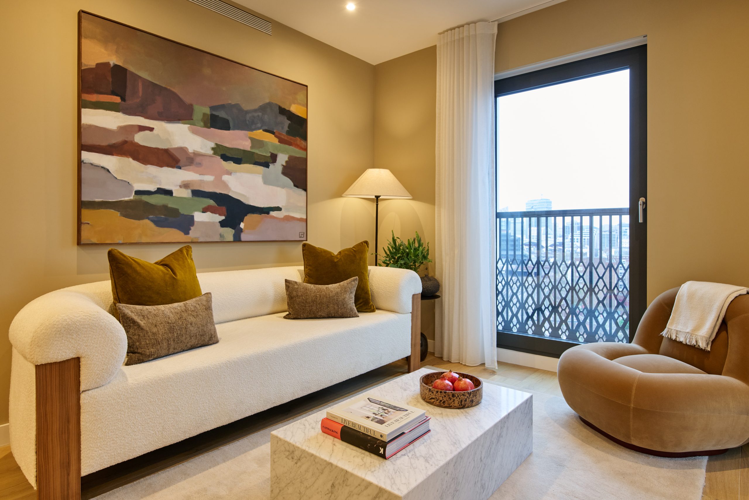New apartment living room showing white sofa with cushions, coffee table and armchair and window showing a city view