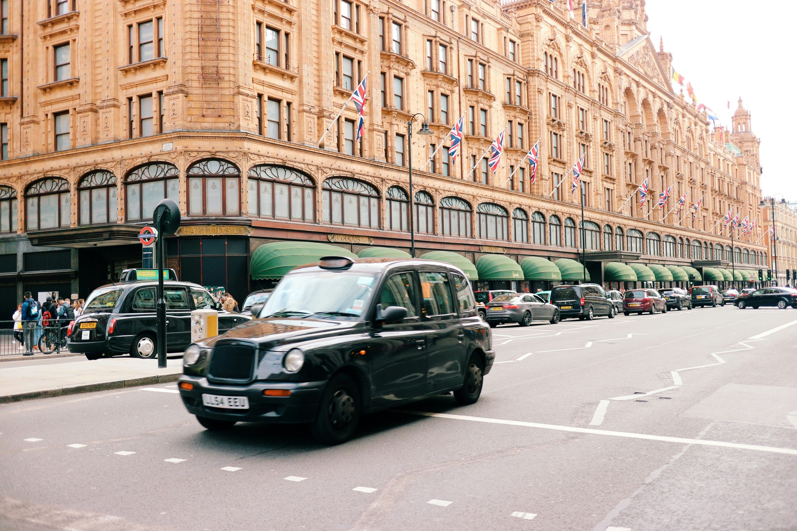 London black taxi driving past Harrods department store in Knightsbridge