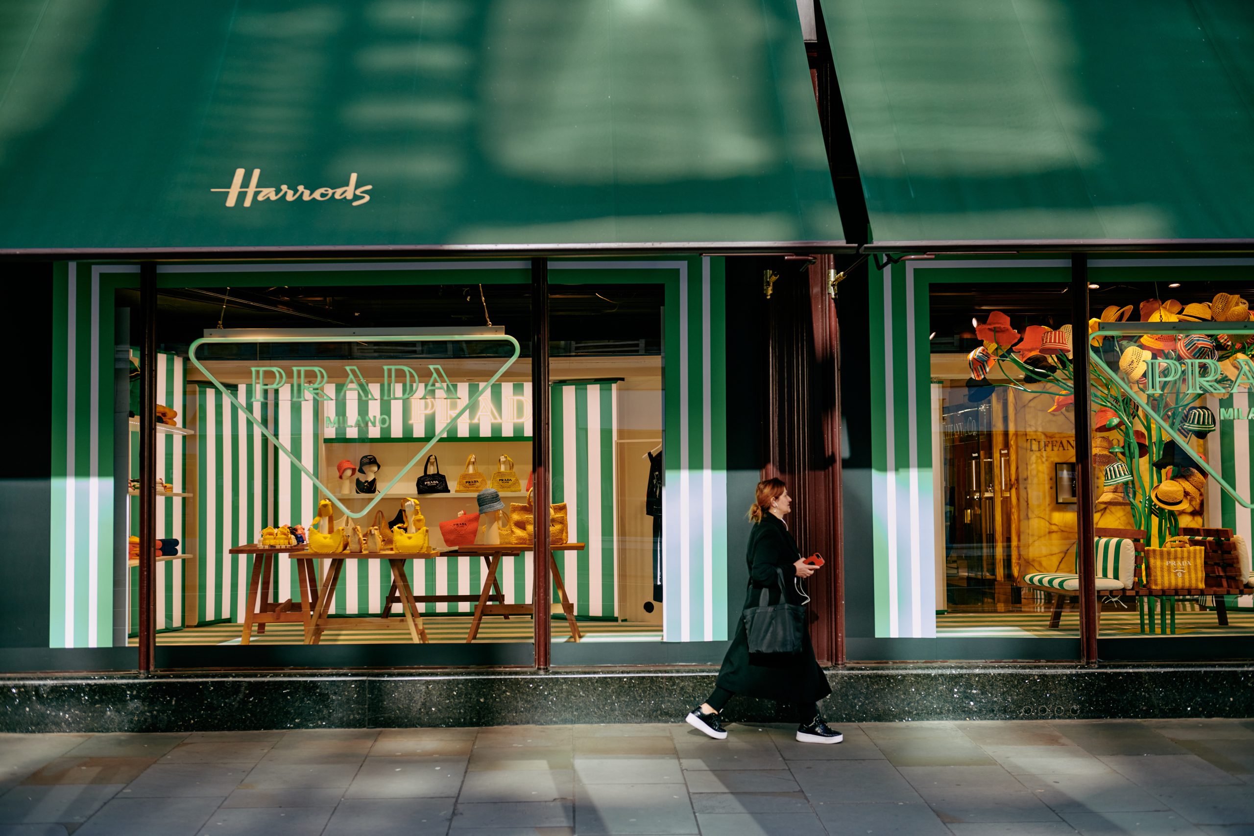 Lady walking past stylish window displays at Harrods department store