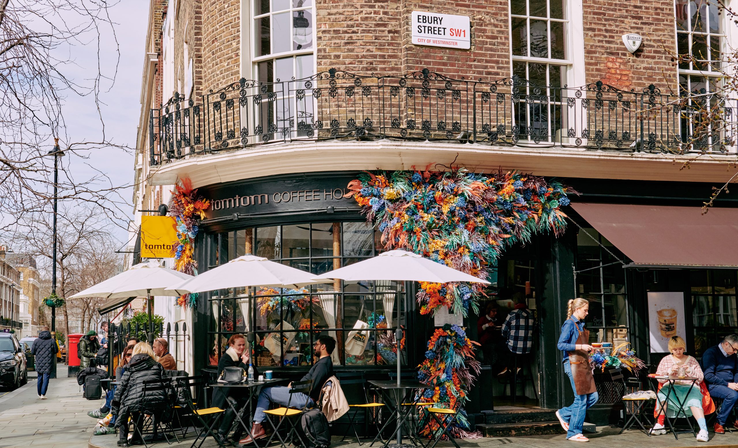 People enjoying drinks outside the Thomas Cubitt pub while a waitress serves food orders