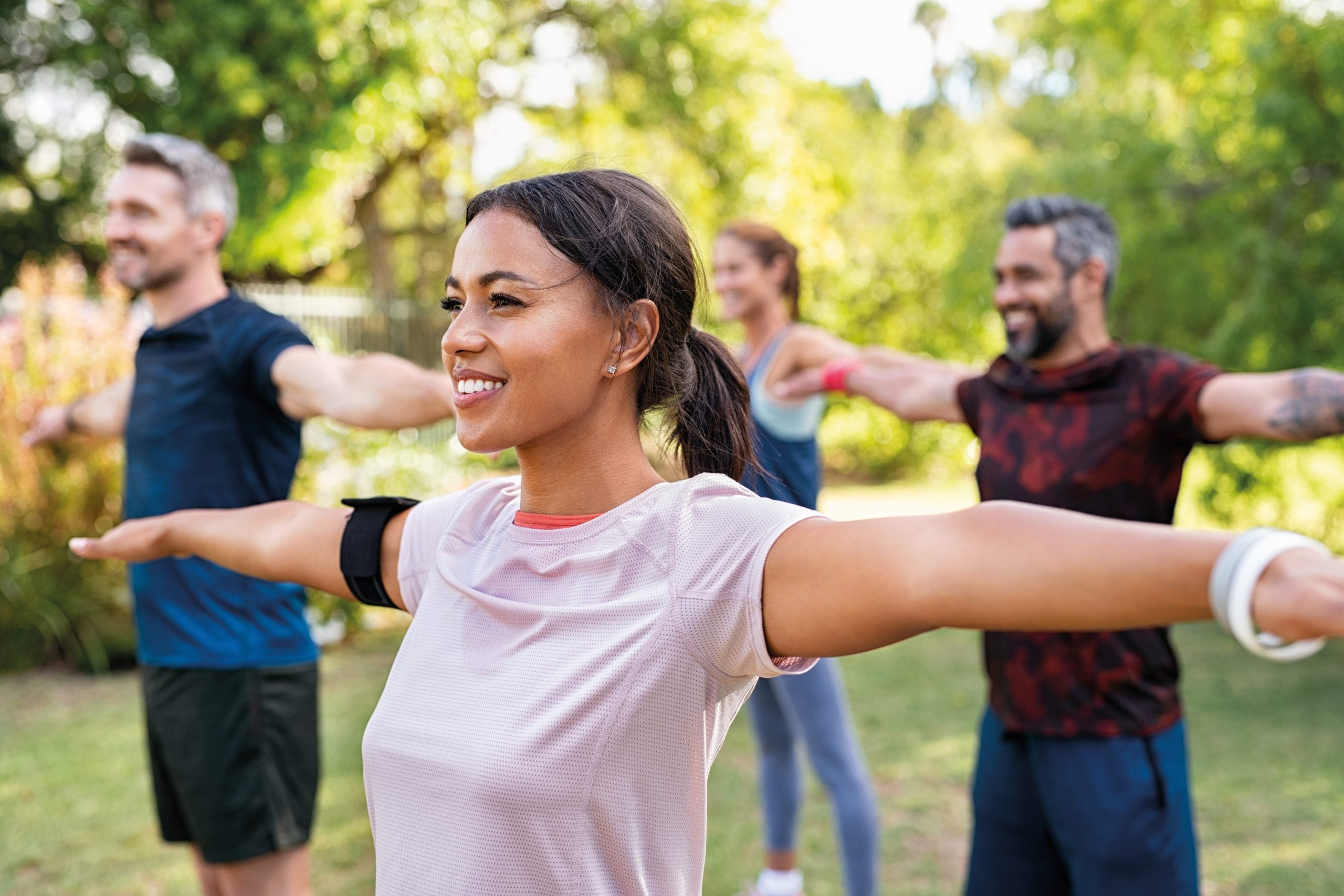 Group of four people doing exercise in an outdoor park setting