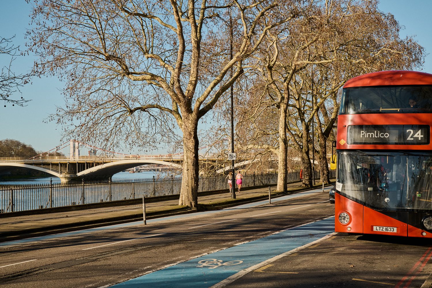 London bus heading along Grosvenor Road, SE15 with the River Thames and Chelsea Harbour Bridge in the distance