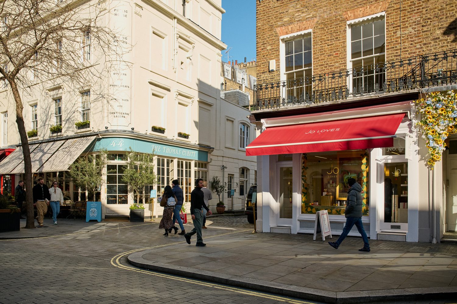 People walking along Elizabeth Street past smart cafes and shops on a sunny morning