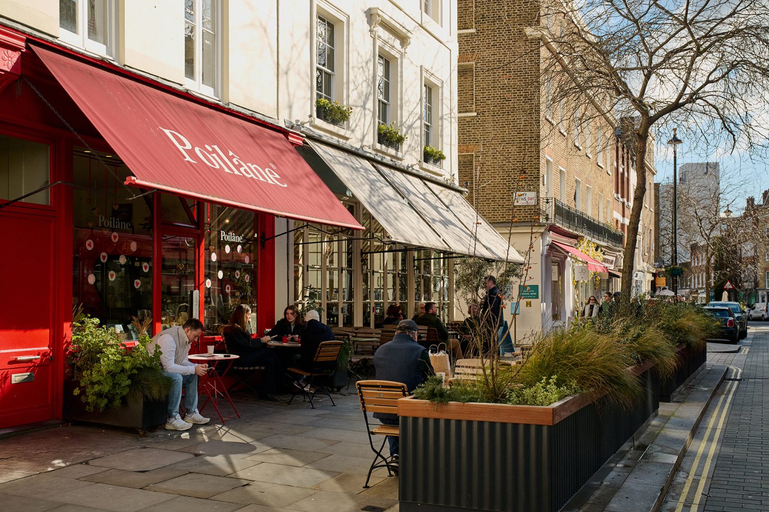 View of Elizabeth Street showing shops and cafes with a focus on a bakery with a red shop front and awning.