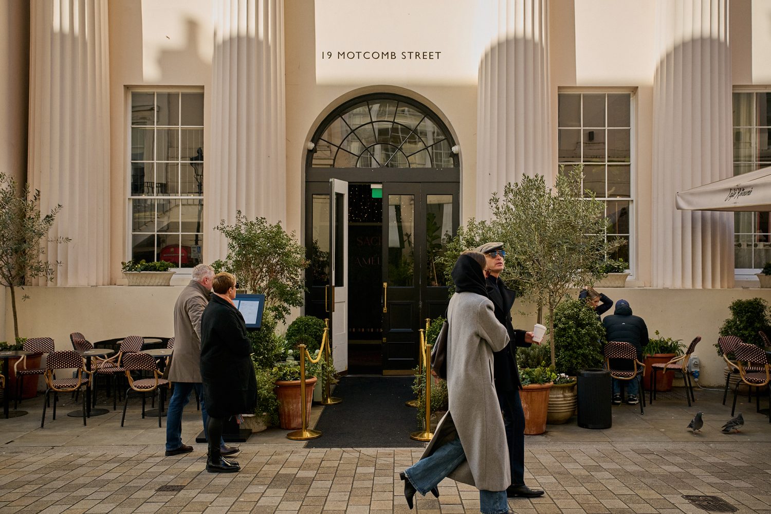 Smartly dressed couples outside the entrance to Pantechnicon, a Grade II-listed, five-storey dining and cultural venue on Motcomb Street in Belgravia, London