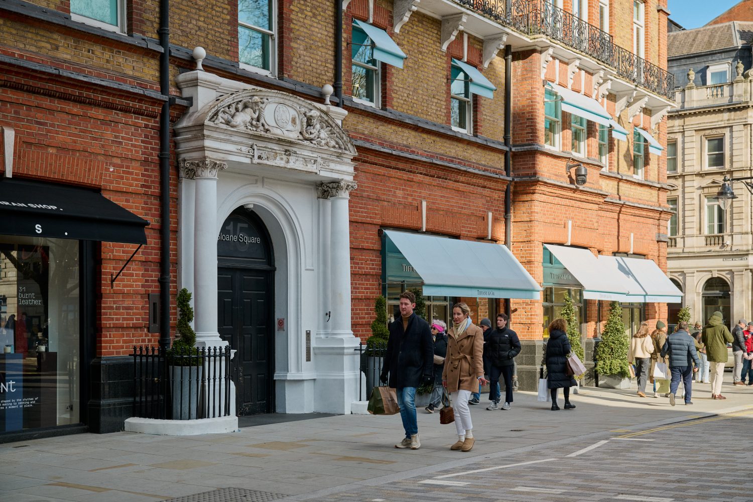 Smartly dressed shoppers outside red brick building in Sloane Square