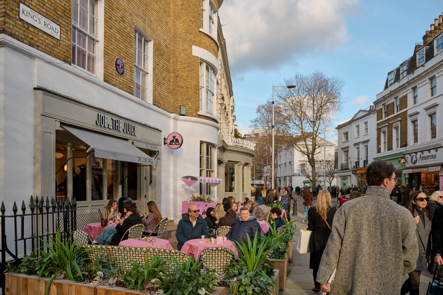 Looking along King's Road with a cafe on the corner with people drinking coffee outside and lots of shoppers walking past