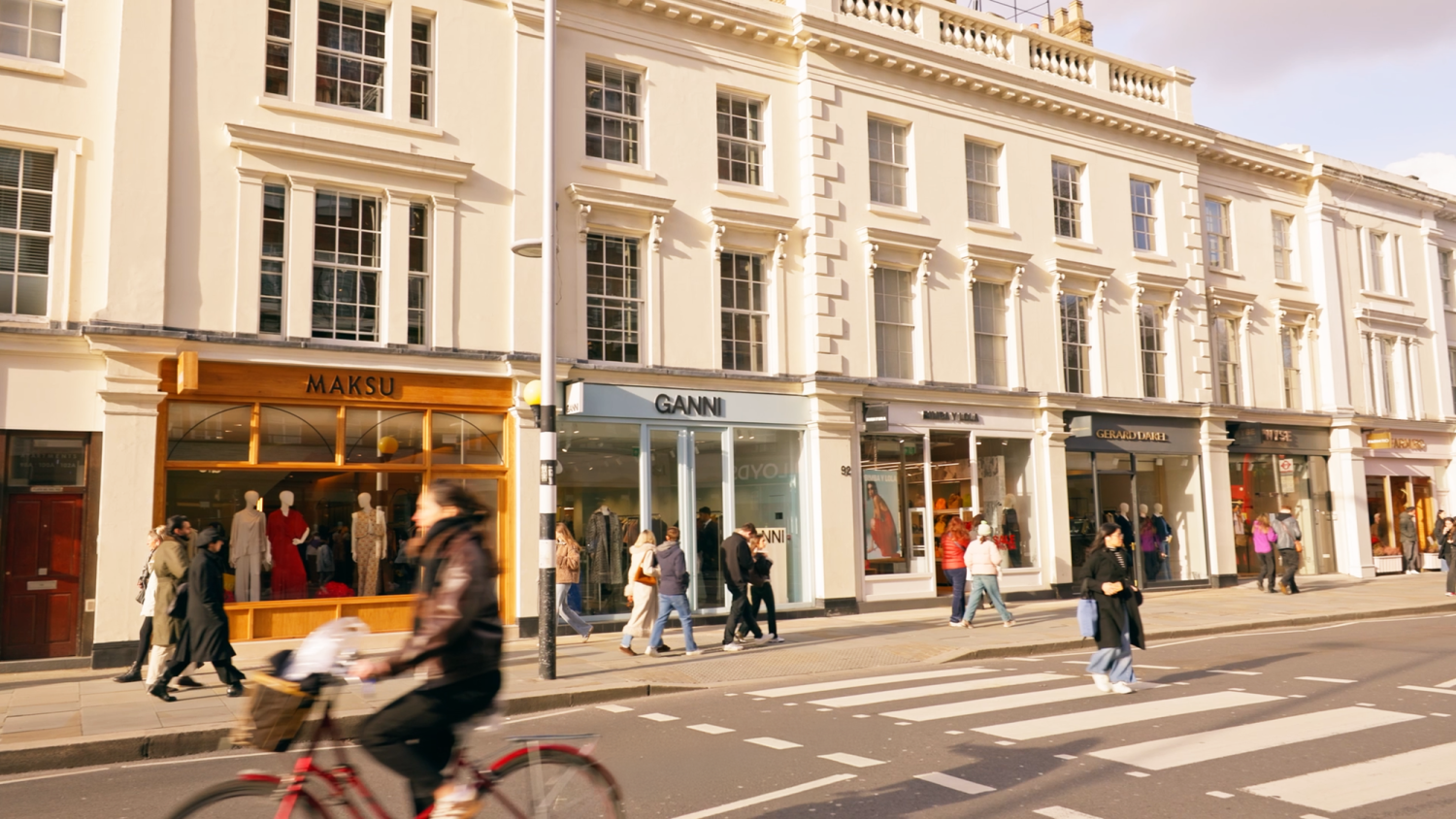 Parade of shops on King's Road with people on a zebra crossing and a lady riding past on a bike